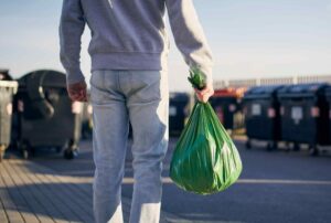 Man carrying garbage bag to garbage bins